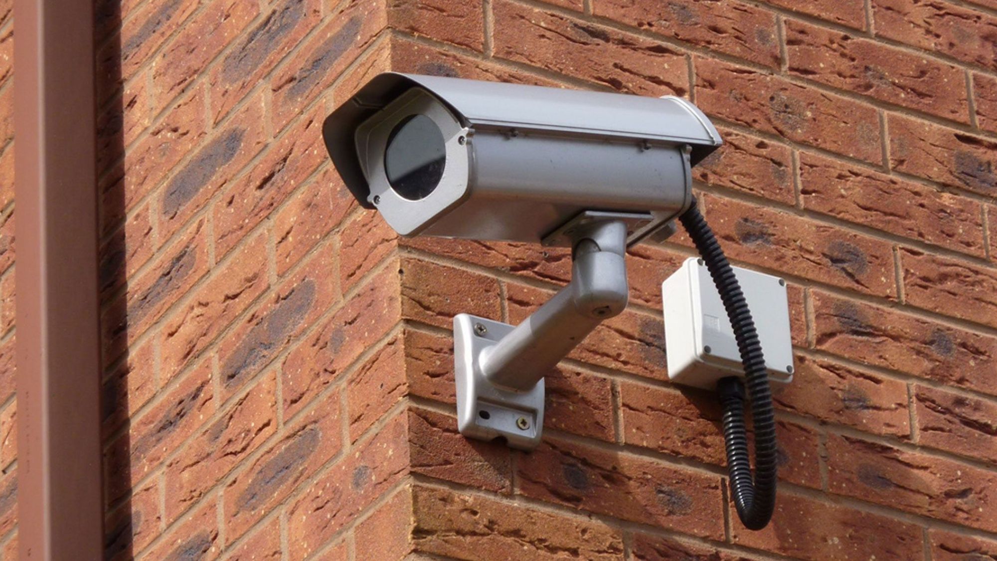 A CCTV camera fixed on a red bricks wall in a construction site