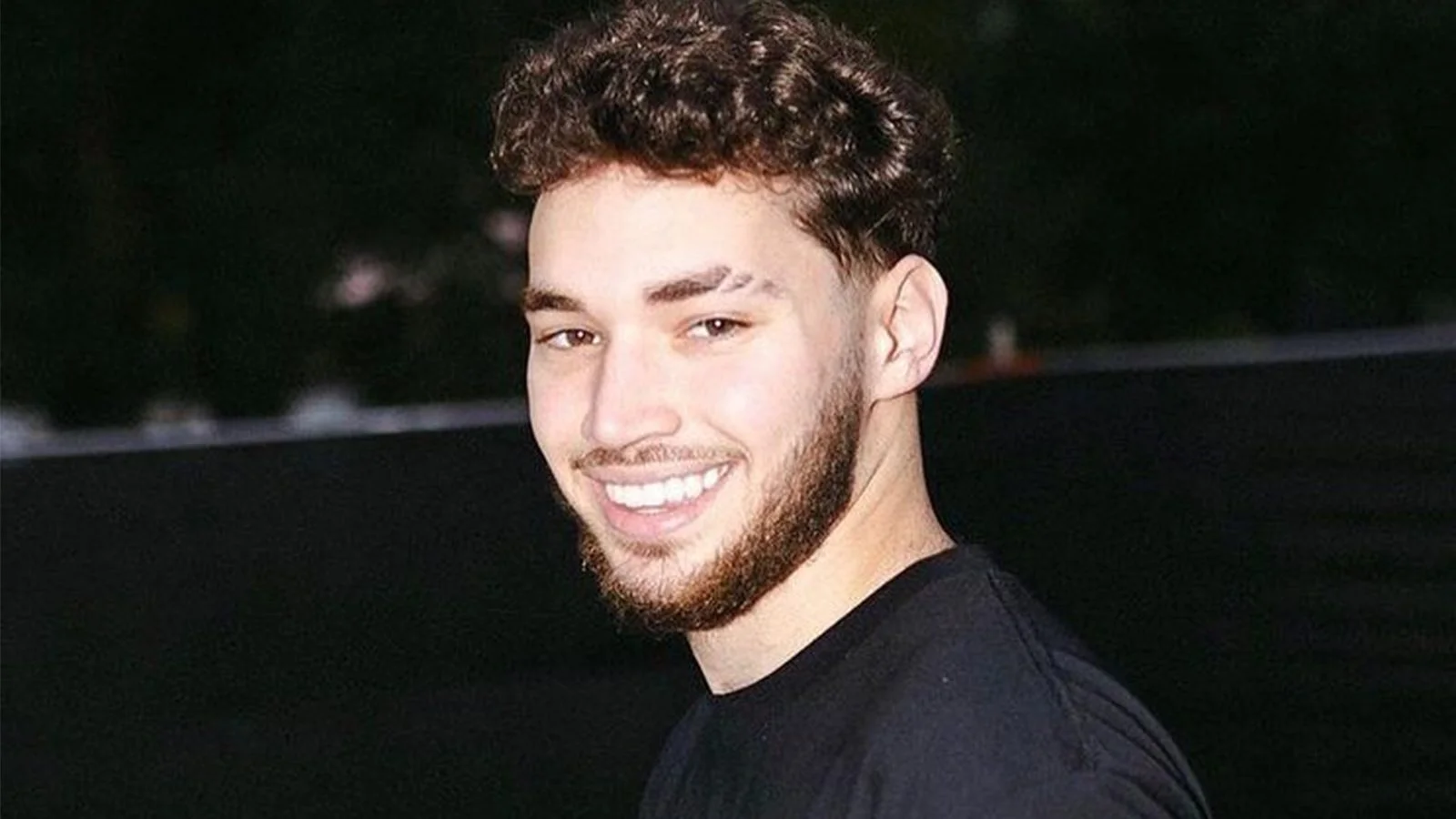 Adin Ross holding a microphone during a podcast recording